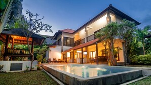 A two-story house with a swimming pool, outdoor seating, and a covered patio area.
