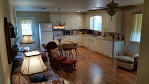 A spacious kitchen with white cabinets, a dining area with a table and chairs, and a ceiling fan.