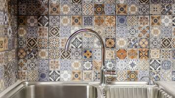 A kitchen with a stainless steel sink and a decorative tiled backsplash.