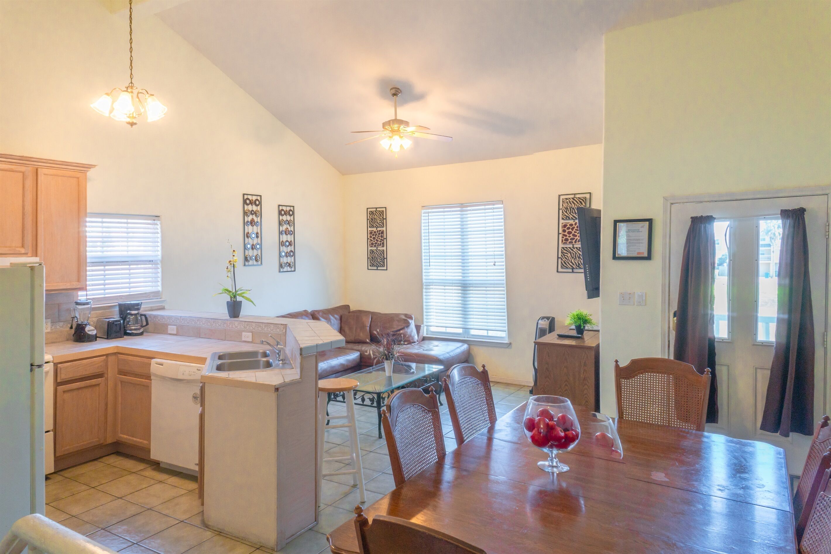 A kitchen with a dining area, a ceiling fan, and a refrigerator.