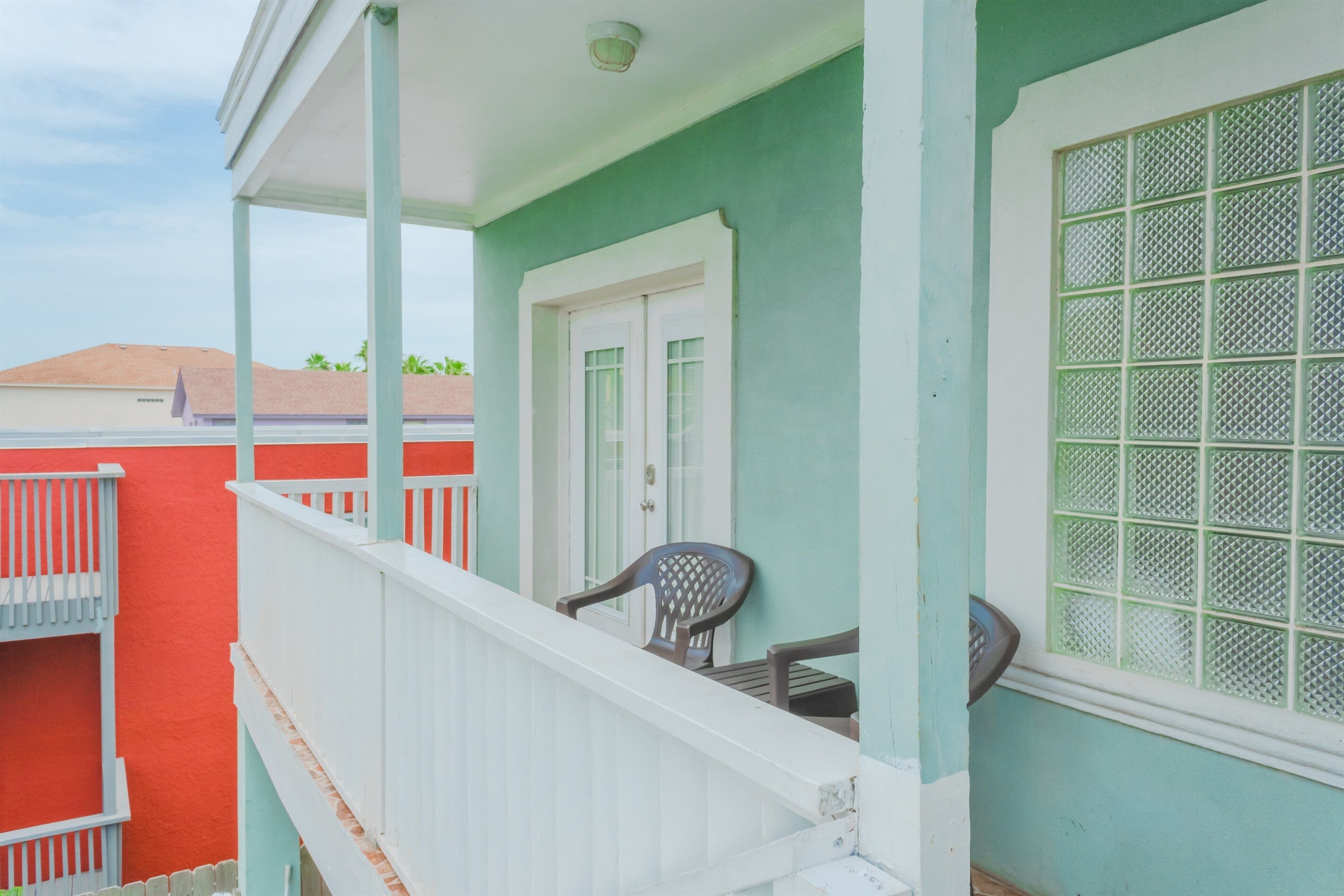A balcony with white railings, a door, and a window with a grid pattern.