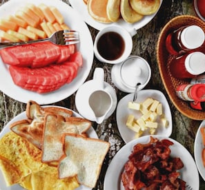 A breakfast spread with pancakes, bacon, toast, eggs, and fruit.