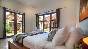 A bedroom with a bed, a wooden bench, and a view of a courtyard through large windows. - 7BR-Last Minute Deal 50%+ OFF!! Nusa Dua (Bali)
