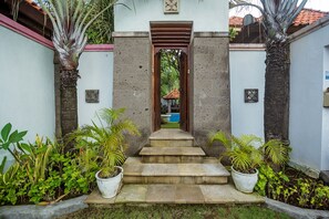 Un sendero que conduce a la entrada de un edificio, con escalones y macetas a ambos lados.