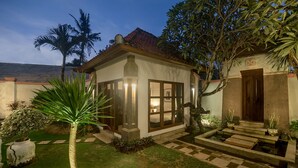 A small, well-lit house with a tiled roof, surrounded by a garden with a palm tree and a water feature. - 7BR-Last Minute Deal 50%+ OFF!! Nusa Dua (Bali)