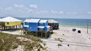 A beachfront property with multiple wooden structures elevated on stilts, featuring balconies and a sandy beach area. - enJoy | gulfside, great price, open starting 8/8 (Dauphin Island)