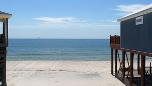 A beach view with a wooden pier and a blue building. - enJoy | gulfside, great price, open starting 8/8 (Dauphin Island)
