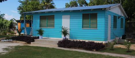 Una casa pequeña de un solo piso con fachada azul y puerta blanca.