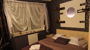 A bedroom with a large bed, a window with sheer curtains, a radiator, and a wall-mounted mirror. - Torun Apartment Modern apartment in the Torun city center (Jakubskie Przedmiescie)
