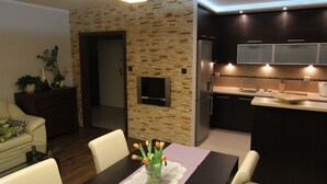 A modern kitchen with dark cabinets, a built-in oven, and a central island with a sink. - Torun Apartment Modern apartment in the Torun city center (Jakubskie Przedmiescie)