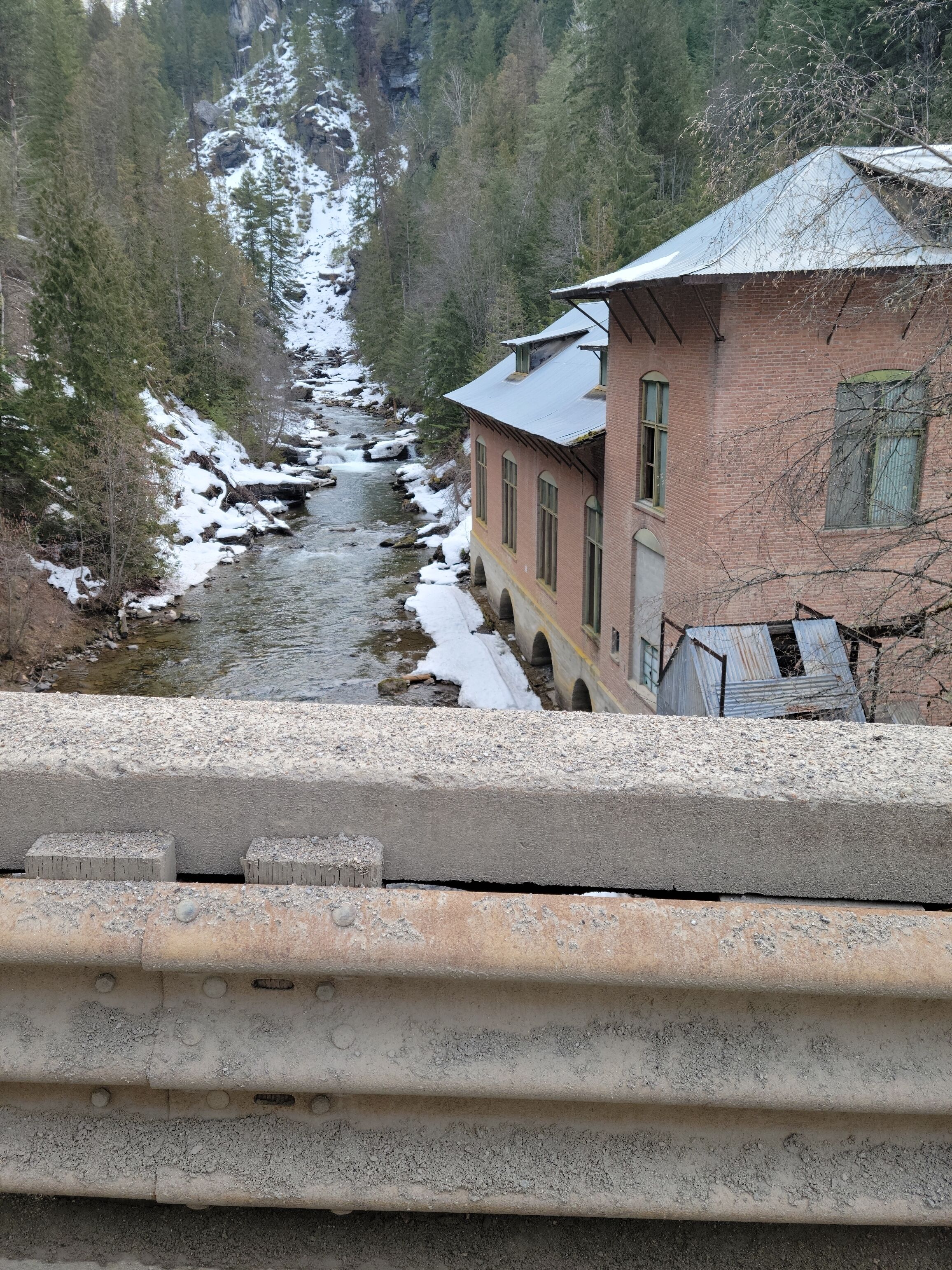 Une rivière traverse une zone boisée, et un bâtiment se trouve à proximité de la rivière.