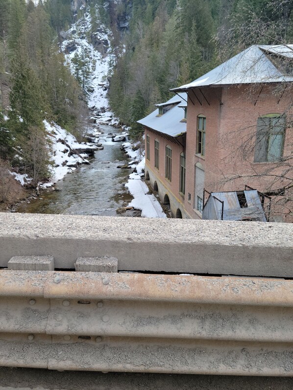 A river flowing through a forested area with a building adjacent to the river.