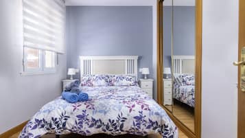 Un dormitorio con cama, mesitas de noche, un espejo y una ventana con persianas.