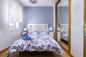 Un dormitorio con cama, mesitas de noche, un espejo y una ventana con persianas.
