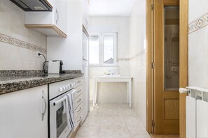 Una cocina estrecha con horno empotrado, una encimera con cafetera y una ventana sobre el fregadero.