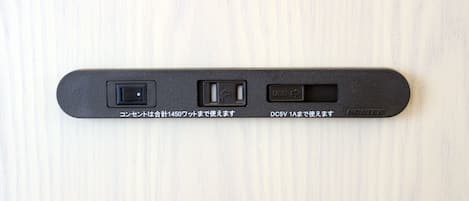 A black device with three ports on a light wooden surface.