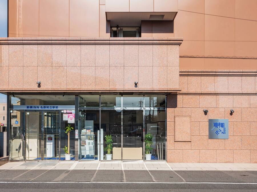 Un bâtiment moderne avec une entrée en verre, des panneaux indiquant « INN » et « AED », et un panneau bleu indiquant l’emplacement.