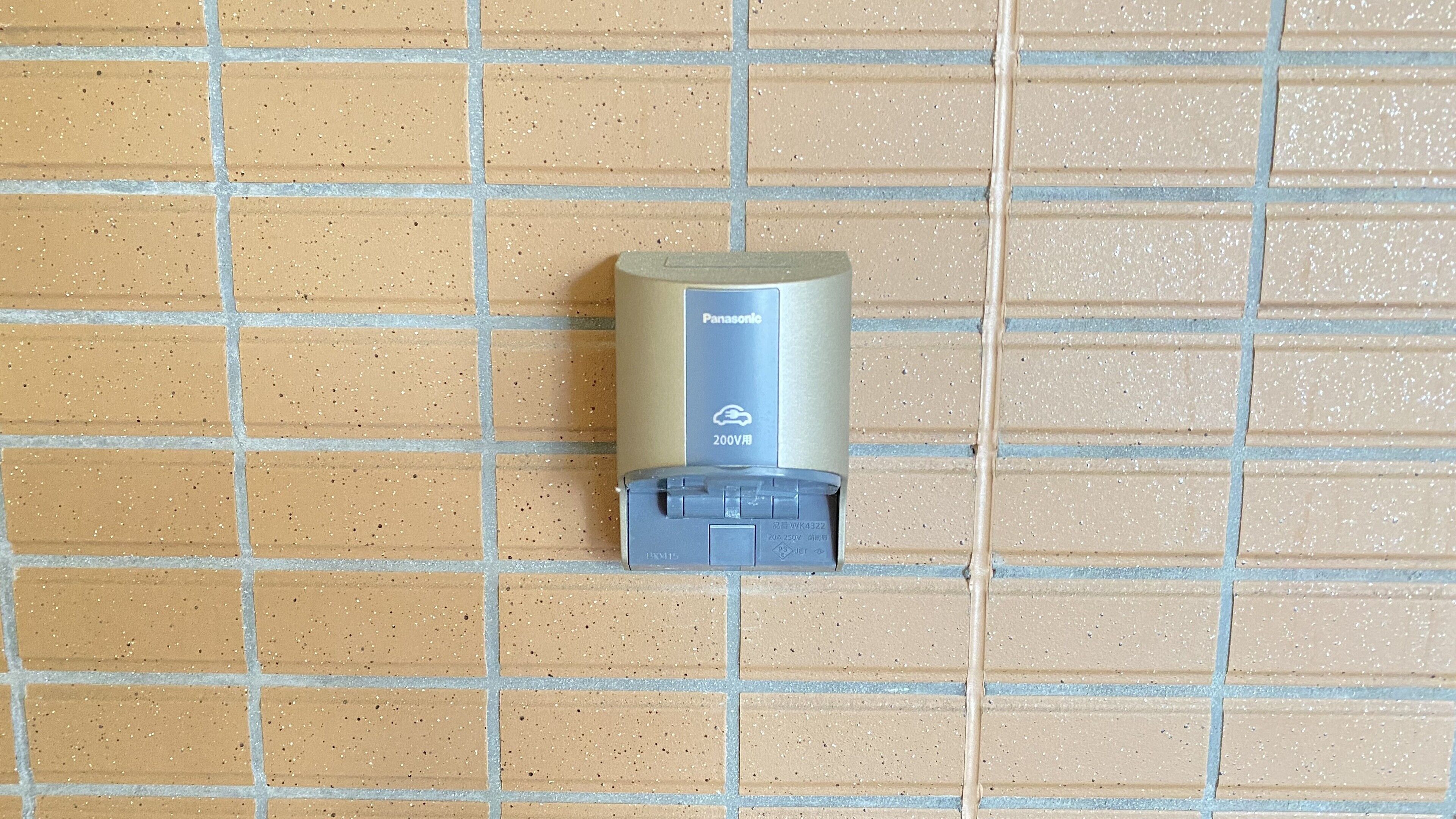 A Panasonic 200V electric outlet mounted on a tiled wall.
