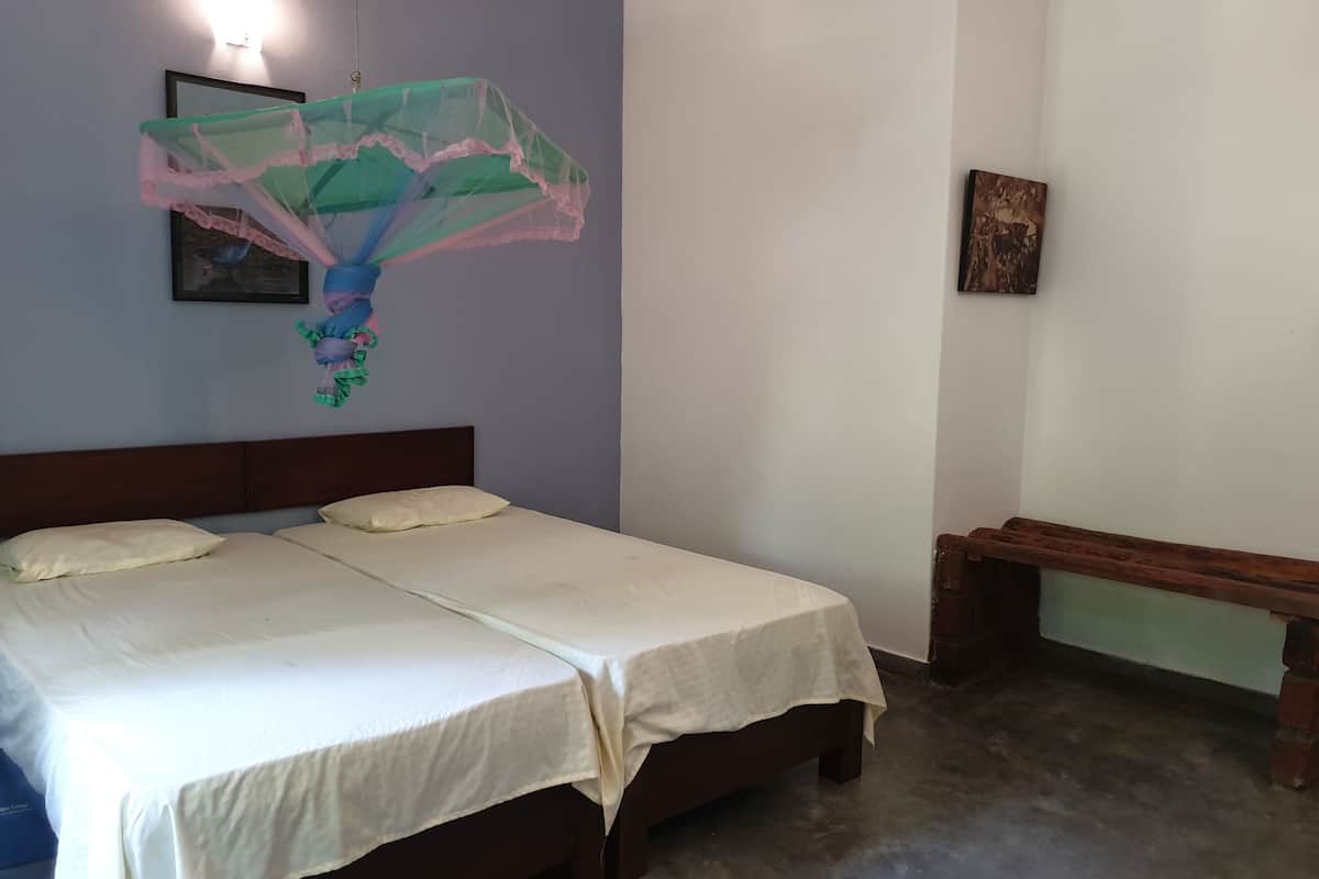 A double bed with white linens, a wooden headboard, and a bench against the wall.