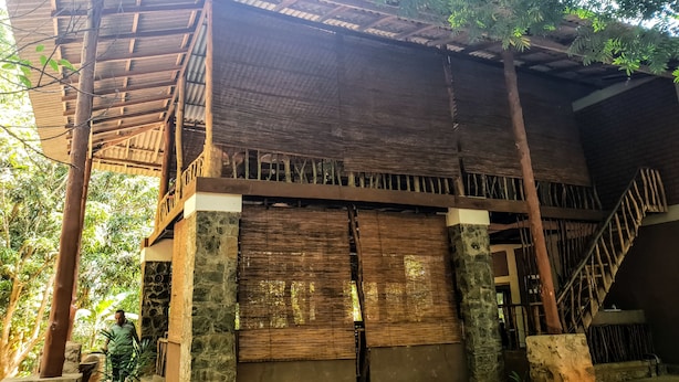 A traditional wooden structure with a thatched roof, stone pillars, and a staircase leading to an upper level. - Jungle House Udawalawe Holiday Lodge (Udawalawa)