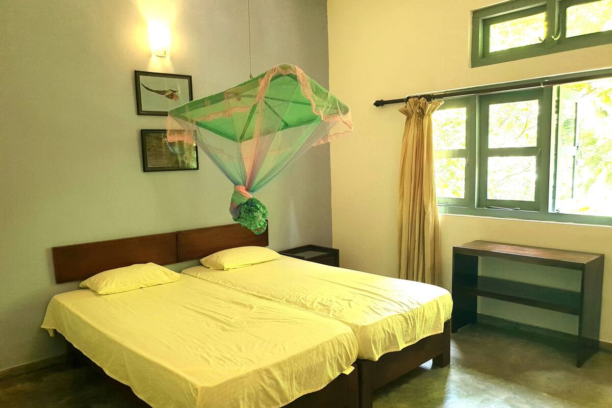 A bed with a canopy, a nightstand, a bedside table, and a window with curtains.
