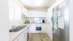 Enjoy cooking in this well-equipped kitchen with a double sink, oven, and refrigerator.