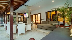 A spacious living area with a sofa, white chairs, a dining table, and a TV. - Magical Estate, Walk to Seminyak Beach (Seminyak)