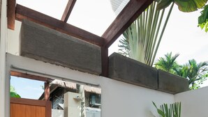 A modern bathroom with a large mirror, a stone sink, wooden cabinets, and a decorative plant. - Magical Estate, Walk to Seminyak Beach (Seminyak)