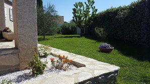 A well-maintained garden with a stone pathway, flower beds, and a variety of plants. - Villa avec jardin et piscine (Fontvieille)