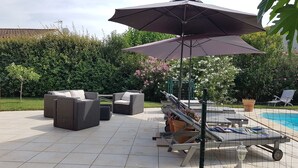 A patio area with a pool, outdoor furniture, and a large umbrella. - Villa avec jardin et piscine (Fontvieille)
