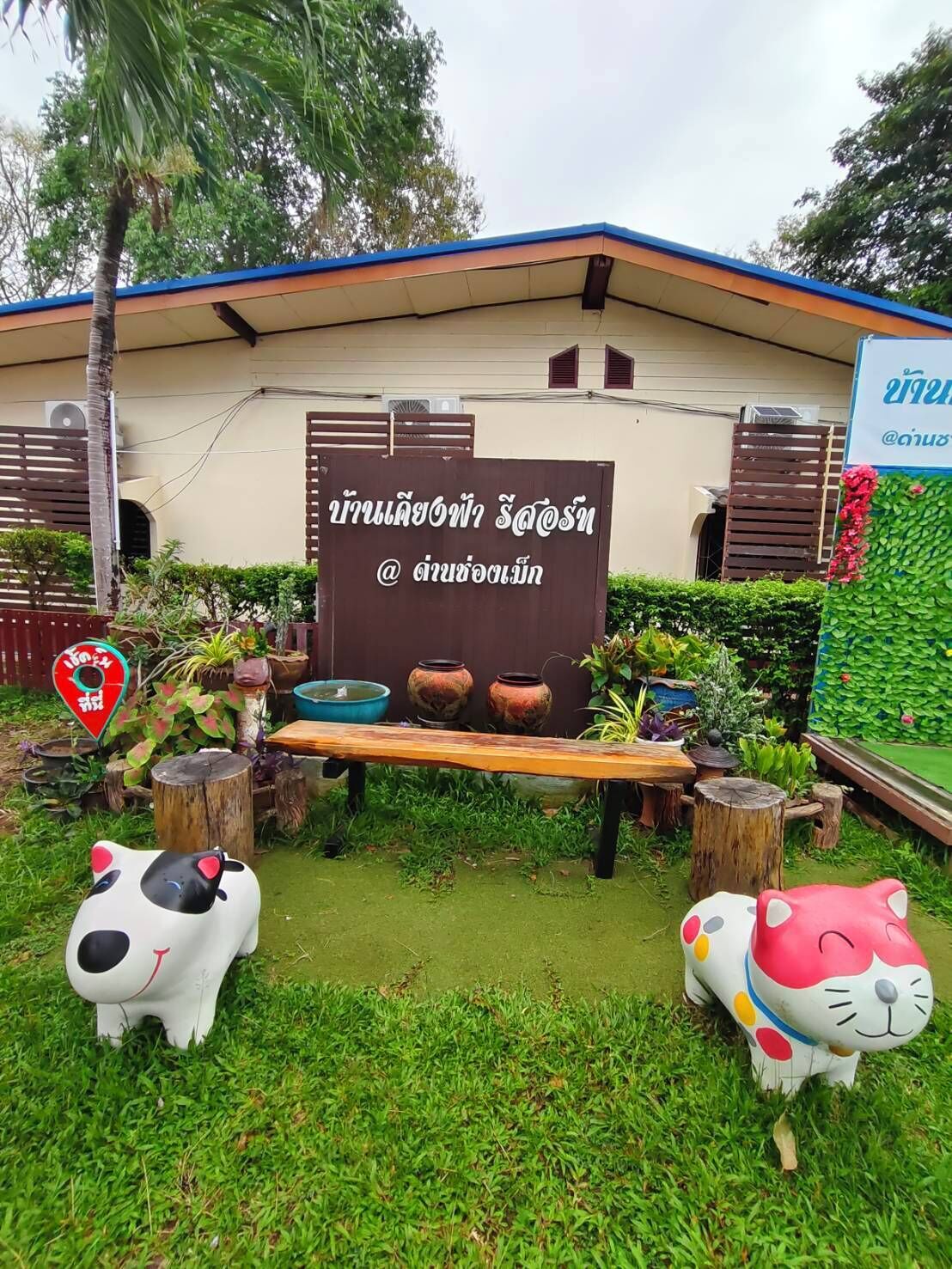 Un jardín con un banco de madera, macetas decorativas y dos estatuas de animales.