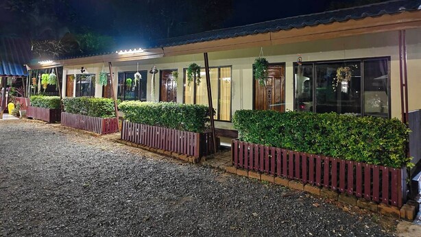 A building with a covered entrance, potted plants, and a gravel driveway. - Ban Kiang Fah Resort Chongmek (Sirindhorn)