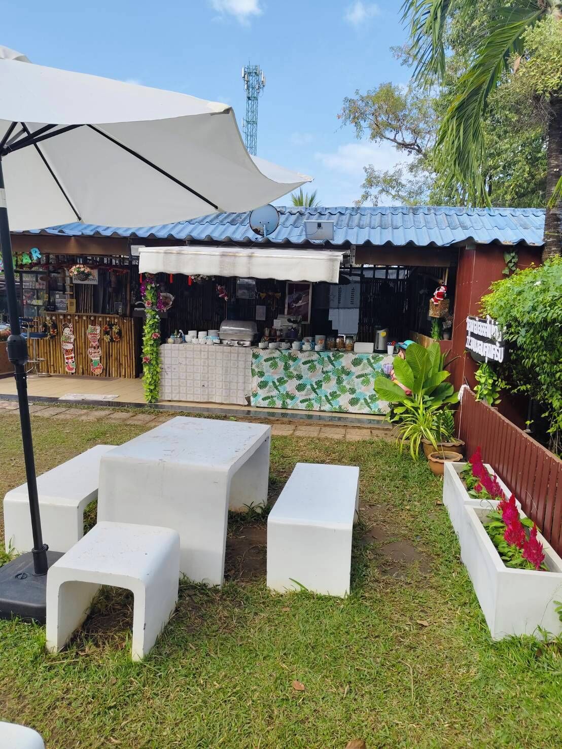 An outdoor seating area with white plastic furniture and a large umbrella.