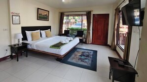 A hotel room with a bed, a desk, a television, and a view of the outside. - Ban Kiang Fah Resort Chongmek (Sirindhorn)