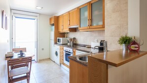 A modern kitchen with wooden cabinets, a built-in oven, microwave, and a sink.