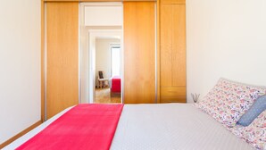 A bedroom with a bed, a wardrobe, and a door leading to another room.