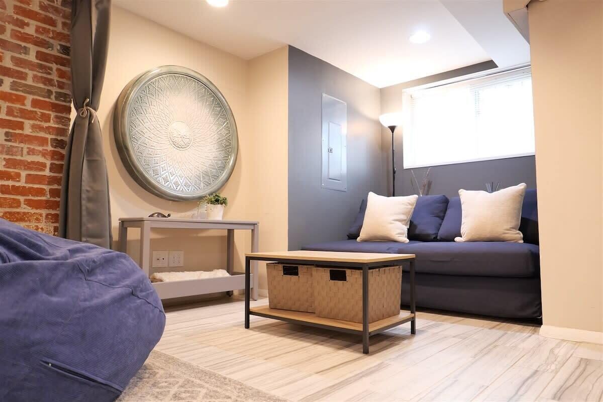A living room with a sofa, a coffee table, a wall art piece, and a window.