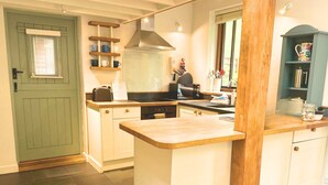 A kitchen with a green door, white cabinets, a wooden countertop, and a window with blinds. - Rural Mezzanine Studio with Shared Swimming Pool, Tennis, Table Tennis & zip wire (Chichester)