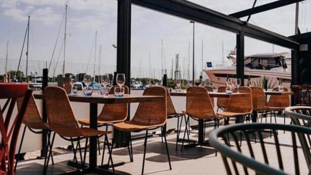 An outdoor dining area with tables and chairs, overlooking a marina with boats. - Rural Mezzanine Studio with Shared Swimming Pool, Tennis, Table Tennis & zip wire (Chichester)