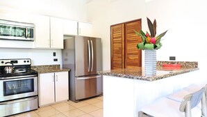 A modern kitchen with stainless steel appliances, a granite countertop, and wooden cabinets.