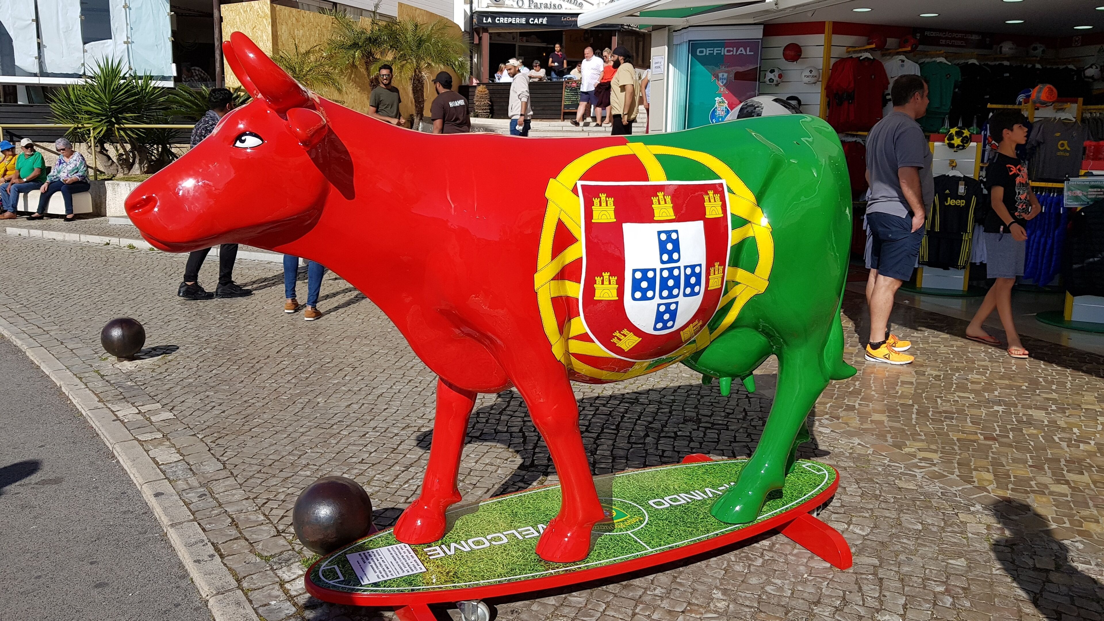Eine Bullstatue mit Wappen auf einem Kopfsteinpflasterweg.
