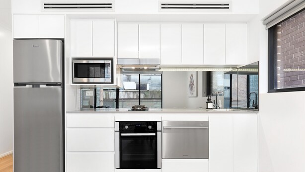 A modern kitchen with white cabinetry, stainless steel appliances, and a dishwasher. - Balmain Modern Apartments (Rozelle)