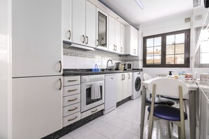 A modern kitchen with white cabinets, a built-in oven, a dishwasher, and a washing machine. - Apartment next to the Plaza Mayor, Wifi and Parking - leonapartamentos (León)