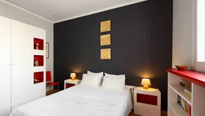 Quarto com cama, duas mesas de cabeceira, guarda-roupa e estante de livros.