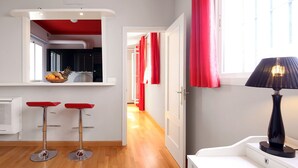 Cozinha moderna com teto vermelho, dois banquetes vermelhos, bancada branca e janela com cortinas vermelhas.