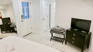 Hotellihuone, jossa on sänky, televisio, työpöytä ja vaatekaappi.