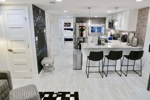 A modern kitchen with white cabinets, a marble countertop, and black bar stools. - Stylish & Modern Apt  Shaw PKING! (Washington)