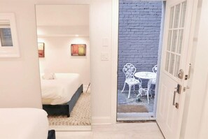A hotel room with a bed, a small table, and chairs outside a door leading to a balcony with a brick wall. - Stylish & Modern Apt  Shaw PKING! (Washington)