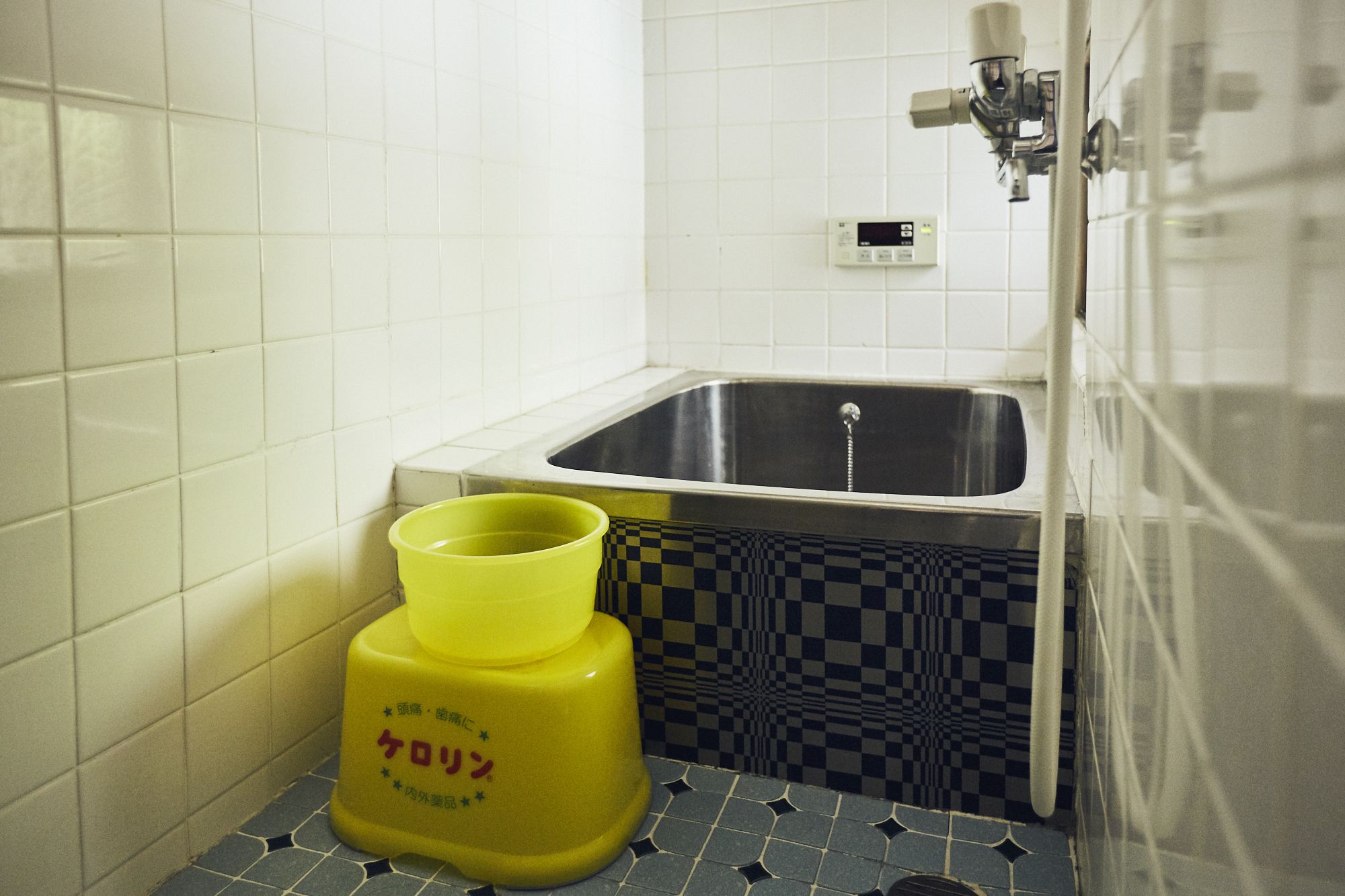 Ein Badezimmer mit Waschbecken, einem gelben Behälter und einem Schachbrettfußboden.