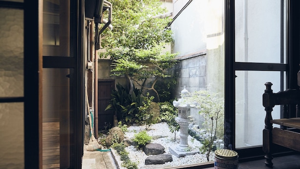 Un jardín japonés tradicional con farol de piedra, bambú y una pequeña fuente de agua.
